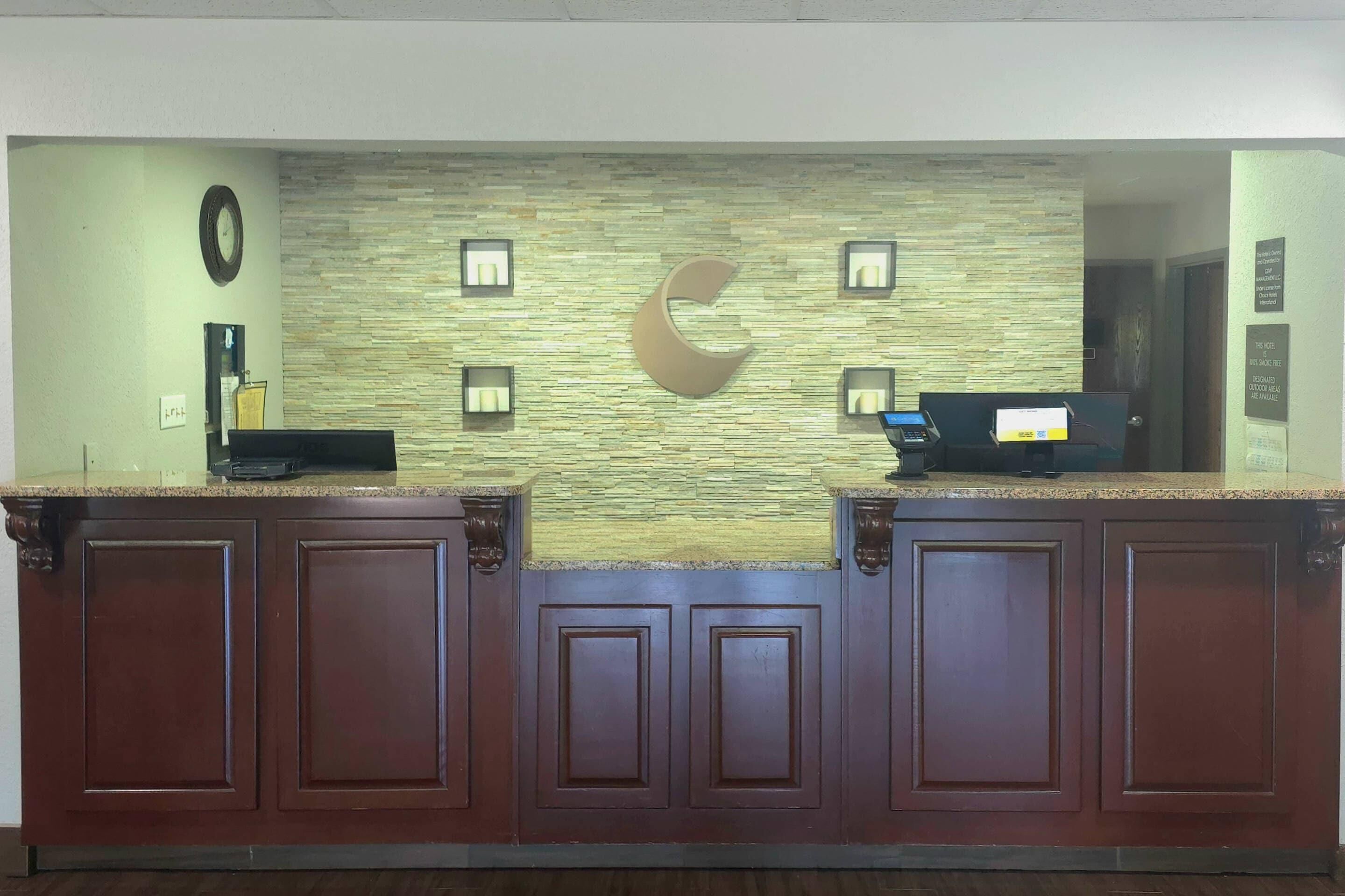 A reception desk with a stone wall, a clock, and a crescent moon design.