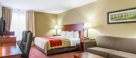 A hotel room with a bed, a desk, a chair, a sofa, and two bedside lamps.