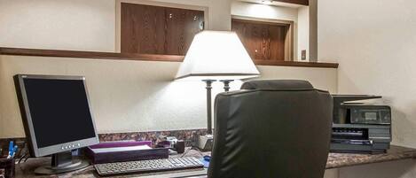 Habitación de hotel con escritorio, computadora, teclado y lámpara.