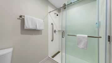 A modern bathroom with a glass shower enclosure, a white towel on a rack, and a toilet.