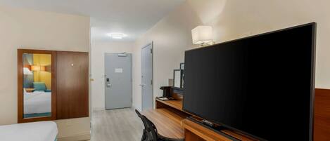 A hotel room with a bed, a desk with a computer, a television, and a wardrobe.