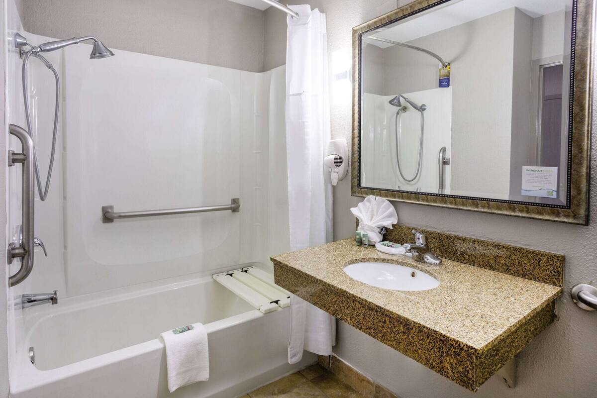 Un baño con bañera, ducha, lavamanos y espejo.
