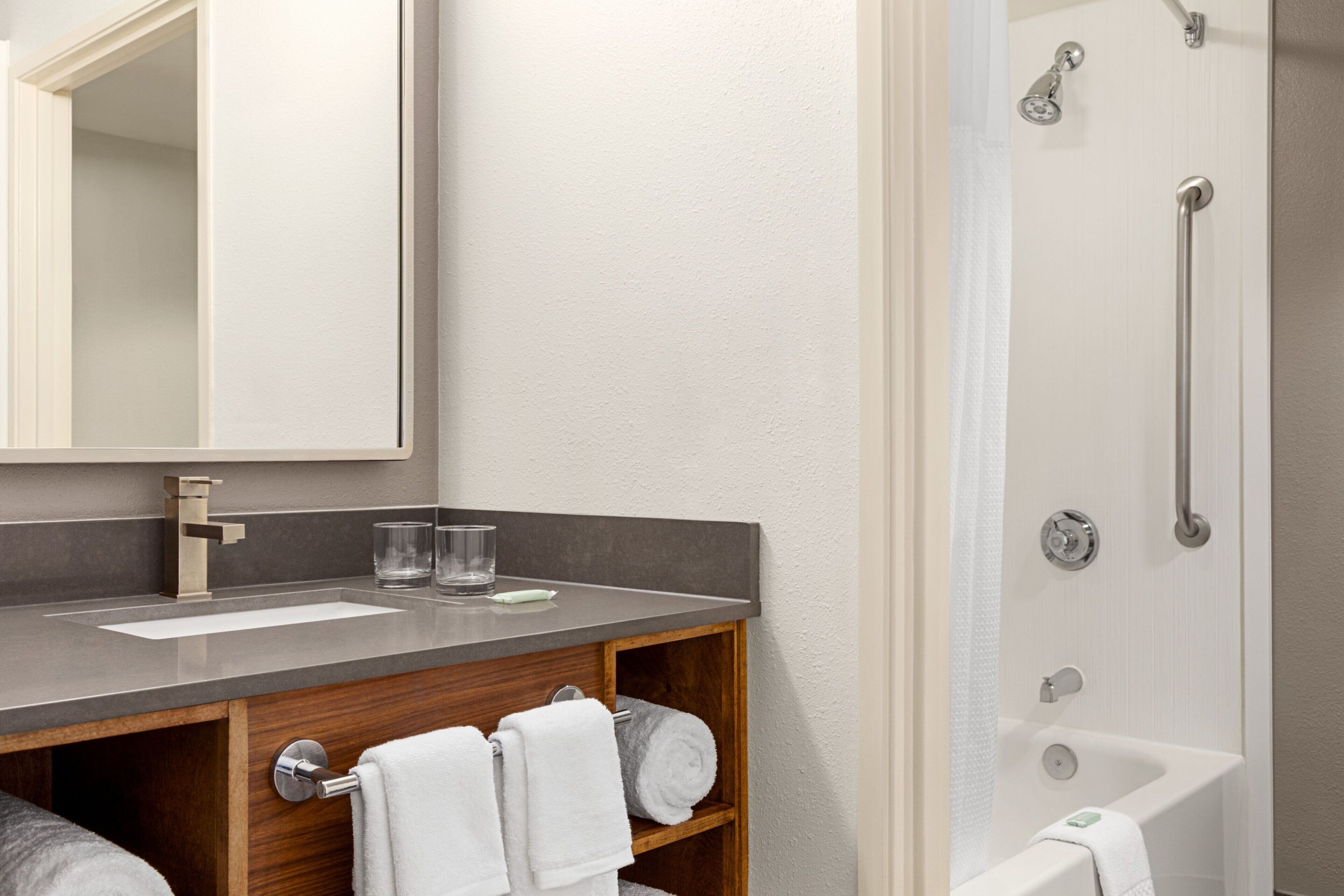 A modern bathroom with a large mirror, a sink, and a shower.