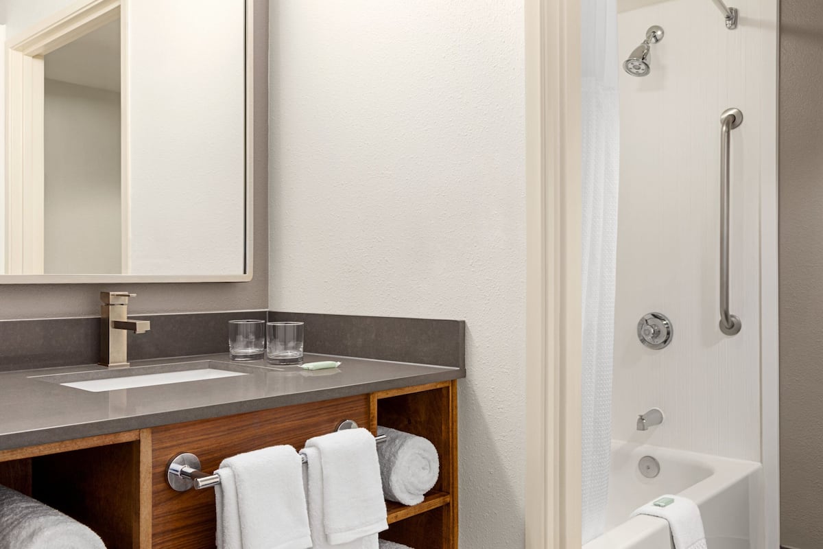 A modern bathroom with a large mirror, a sink, and a shower.
