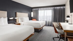 Ein Hotelzimmer mit zwei Betten, einem Schreibtisch und einem Stuhl.