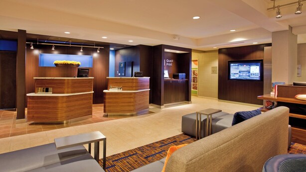 Eine moderne Lobby mit Empfangsschalter, Sitzgelegenheiten und einem digitalen Bildschirm.