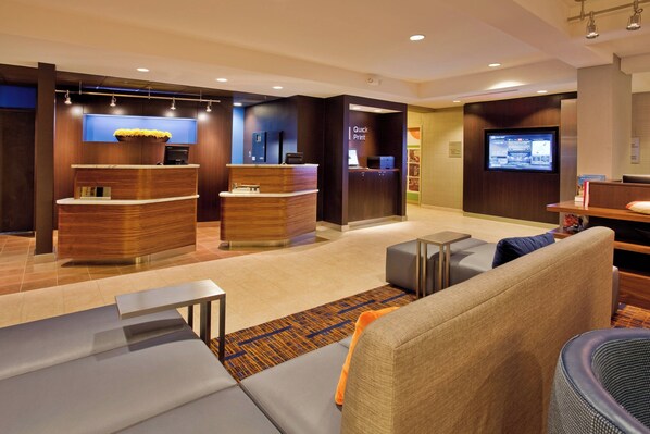 A modern lobby with a reception desk, seating area, and a digital display.