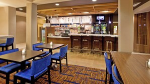 Eine Hotelhalle mit Barbereich, Sitzgelegenheiten und einer Rezeption.
