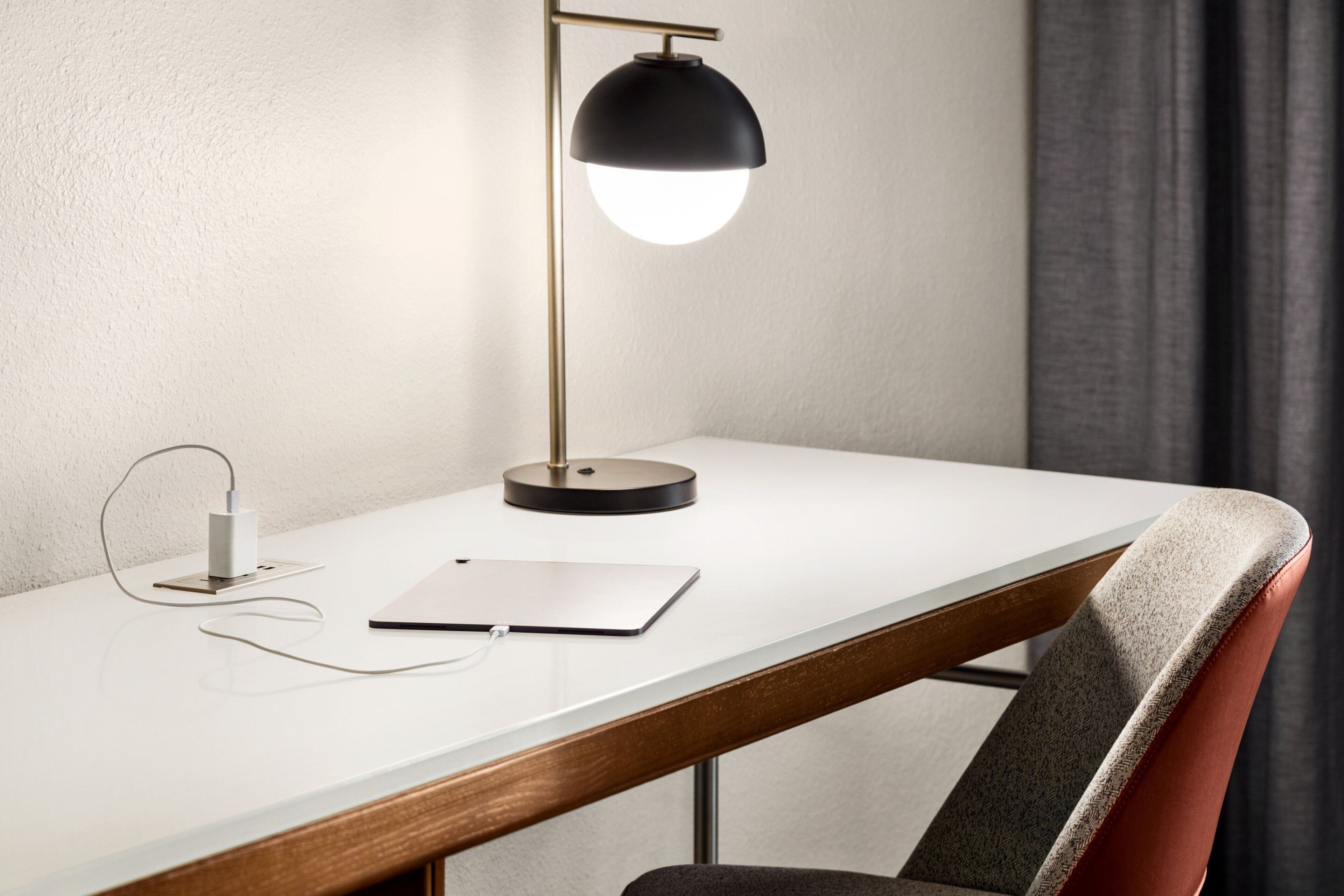 A desk with a lamp, a power strip, and a notebook.