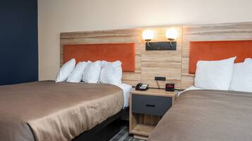 Une chambre d’hôtel avec deux lits, une tête de lit en bois, une table de chevet avec un téléphone et une horloge, et des lampes fixées au mur.