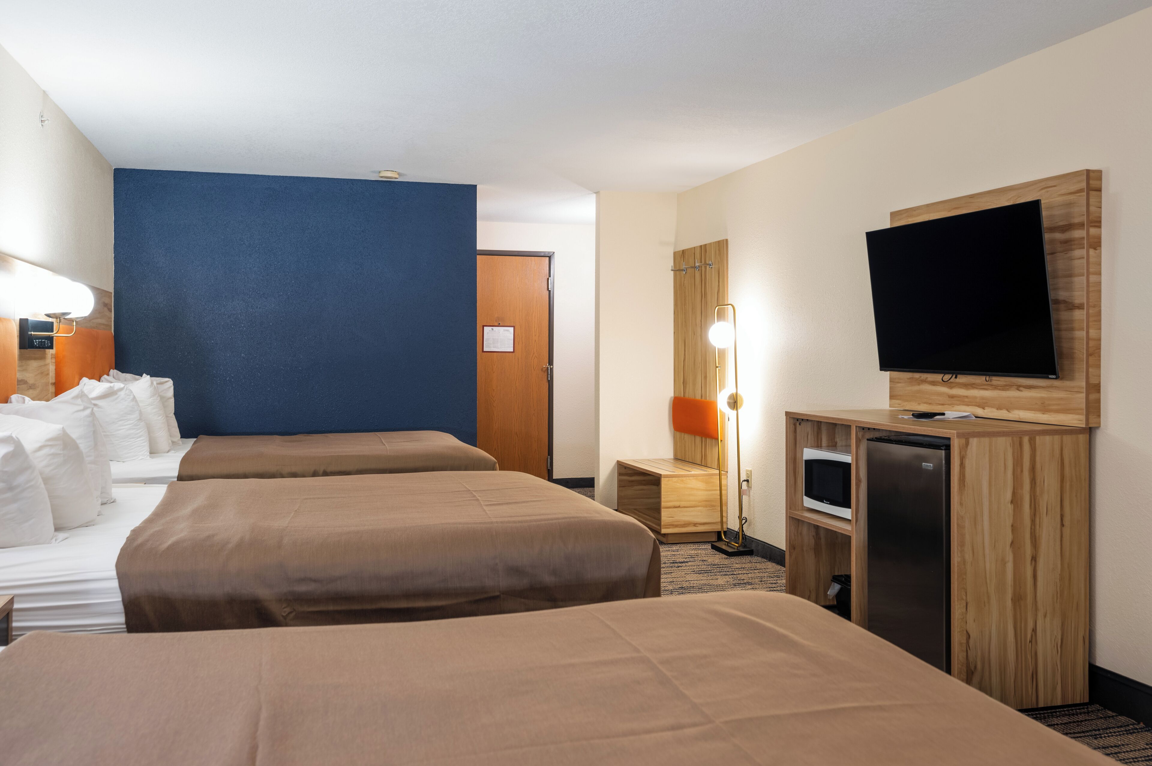 Une chambre d’hôtel avec deux lits, une télévision, un bureau avec une lampe et un réfrigérateur.