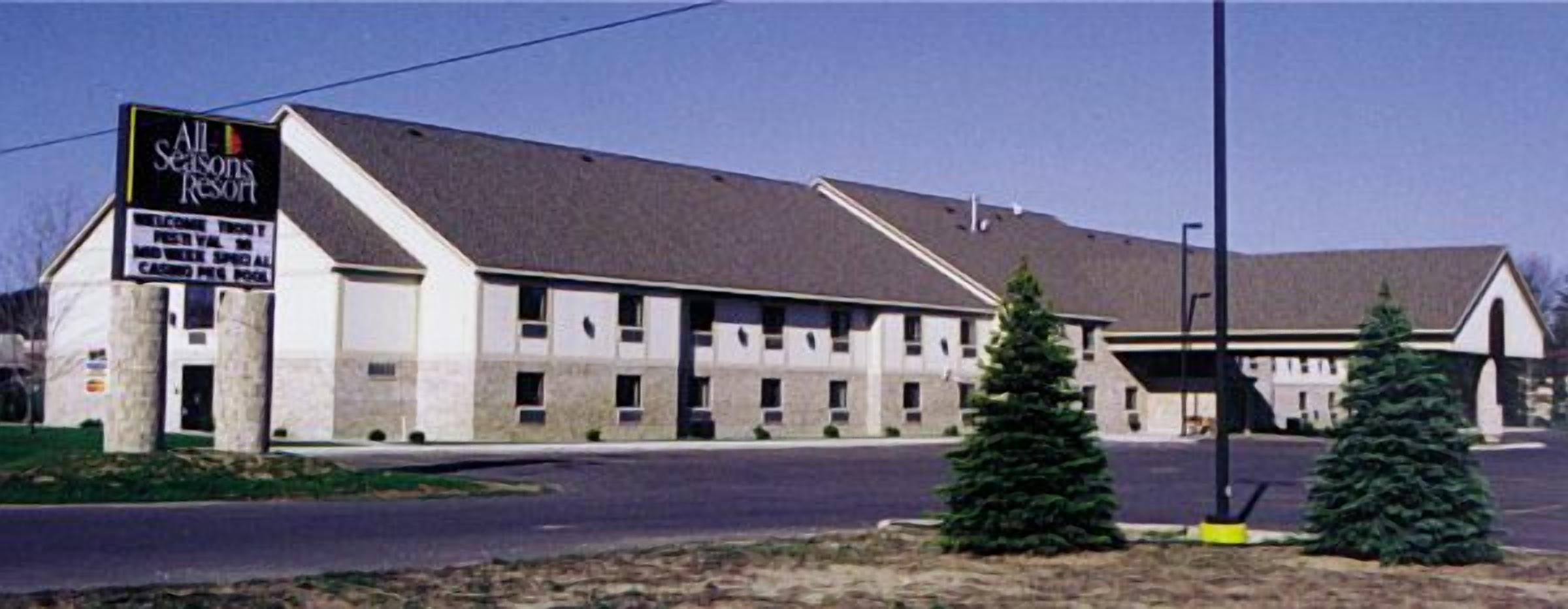 Un motel con letrero, varias habitaciones y un estacionamiento.
