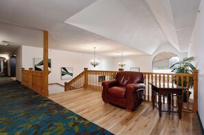 A spacious living area with a wooden staircase, a leather armchair, and a small table.