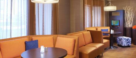 Un rebedor d'hotel modern amb un sofà modular, una taula rodona i una televisió.