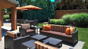 Un patio al aire libre con mobiliario de mimbre, incluyendo sofás, sillas y mesas.