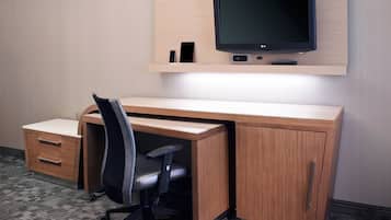 Een modern bureau met een flatscreenmonitor, een smartphone en een afstandsbediening op een houten plank.