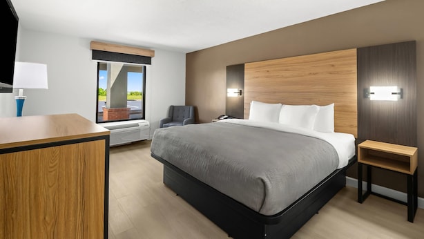 Quarto de hotel moderno com uma cama grande, uma escrivaninha, uma cadeira e vista para o exterior.