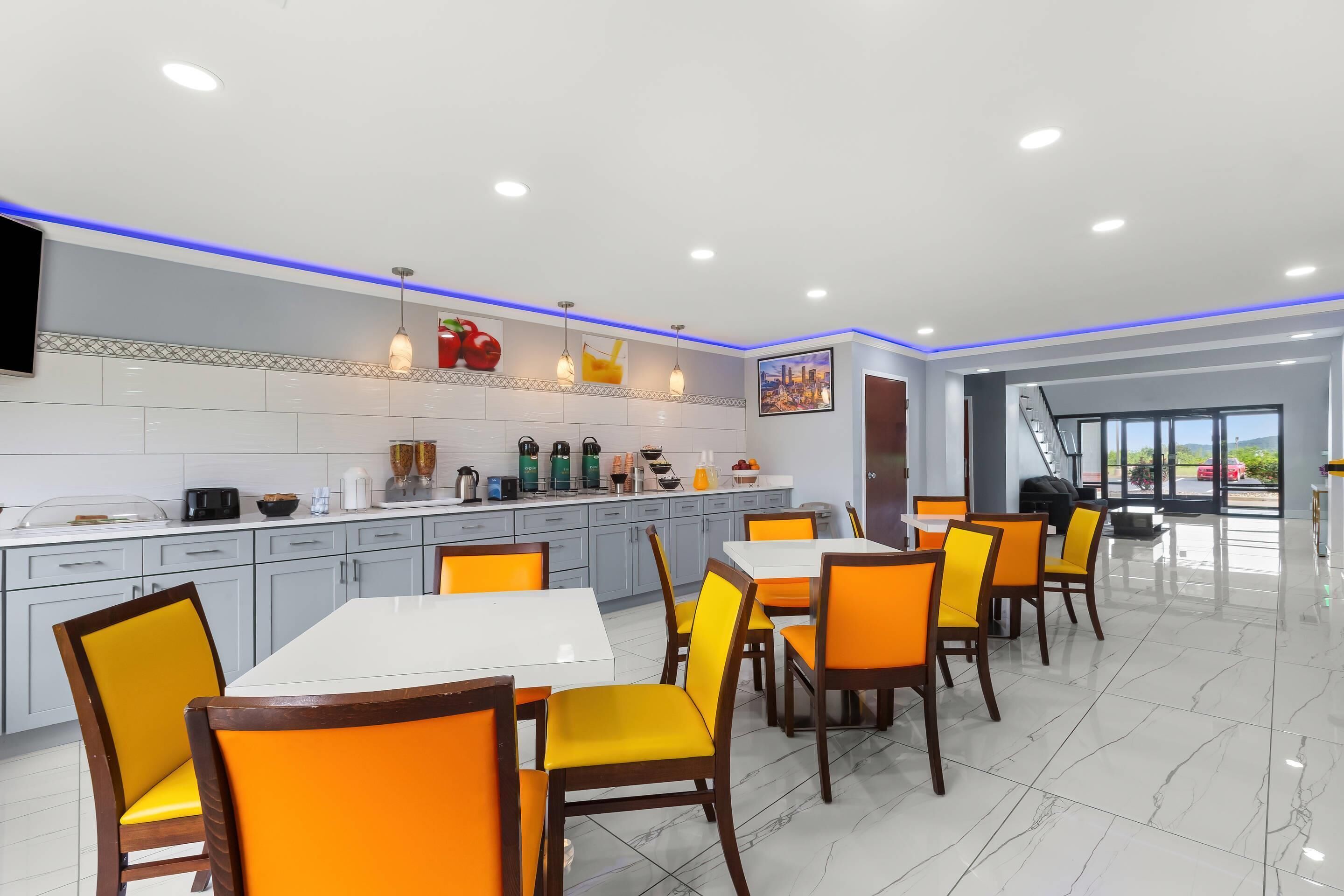 A modern kitchen with white cabinets, a central island, and orange chairs.