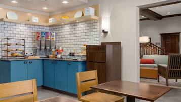Una cocina moderna con armarios azules, una mesa de comedor de madera y un refrigerador.