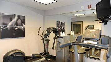 A fitness center with treadmills, elliptical machines, and a water dispenser.