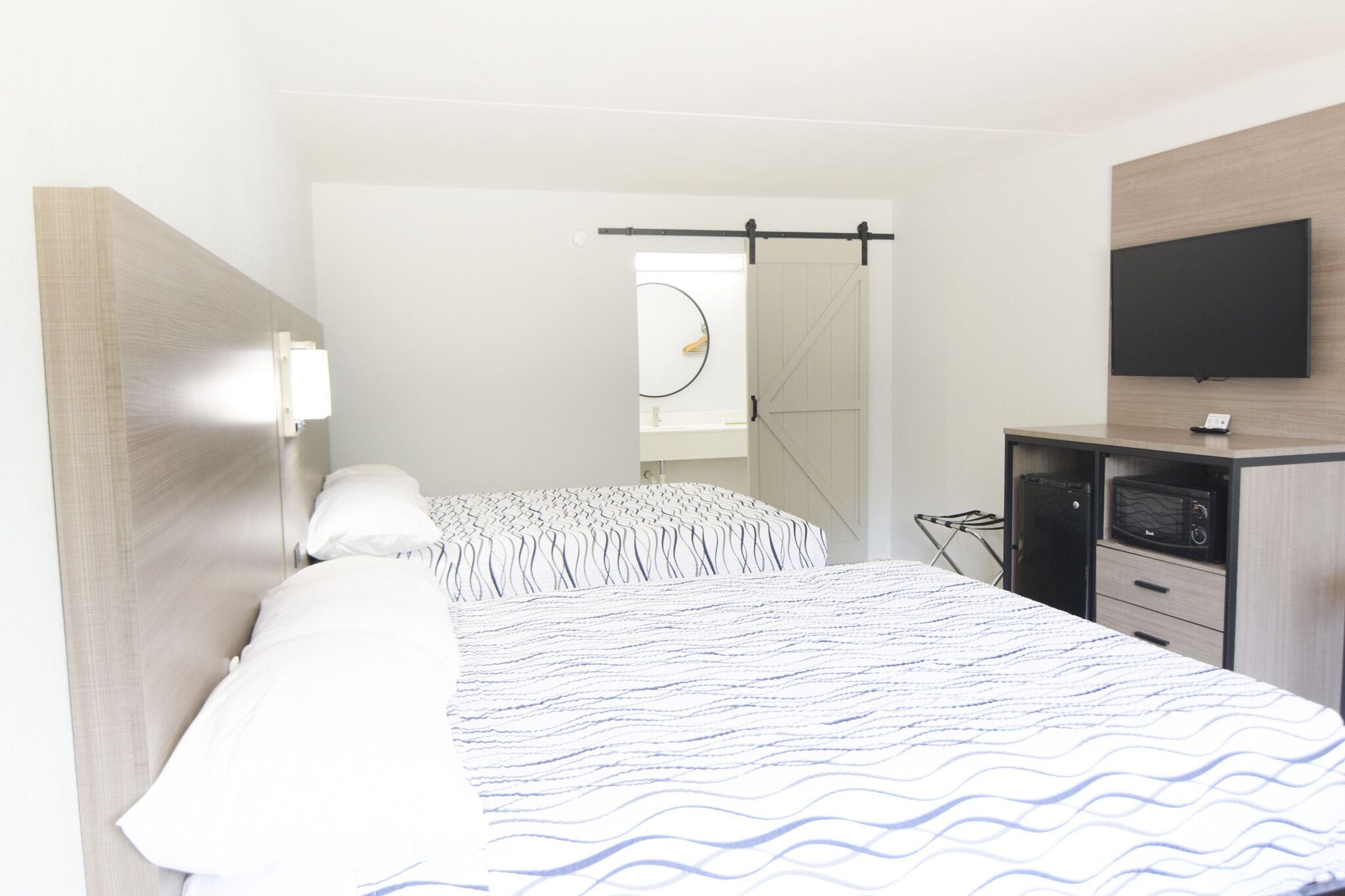 Une chambre d’hôtel avec un lit, un bureau, une télévision et un miroir.