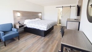 Una habitación de hotel moderna con cama, sofá, escritorio y televisor.