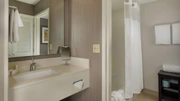 A modern bathroom with a large mirror, a sink, and a shower area.