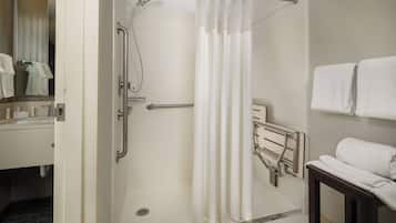 Een hotelbadkamer met een douche, een handdoekhouder en een wastafel.