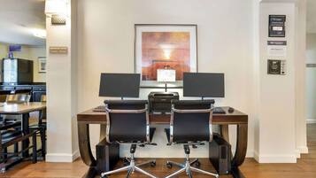 A conference room with two desks, each with a computer and chair, in a hotel setting.