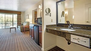 Une salle de bain d’hôtel avec un grand lavabo, un miroir, des toilettes et une douche. Il y a une fenêtre donnant sur l’extérieur.
