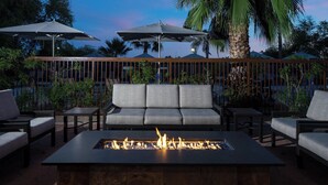 An outdoor seating area with a fire feature, cushioned chairs, and umbrellas. - Courtyard by Marriott Scottsdale North (Phoenix)