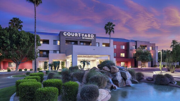 A Courtyard by Marriott hotel with a landscaped entrance featuring a small waterfall and rock formations. - Courtyard by Marriott Scottsdale North (Phoenix)