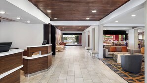 A modern hotel lobby with a reception desk, seating area, and a view to the outdoor patio. - Courtyard by Marriott Scottsdale North (Phoenix)