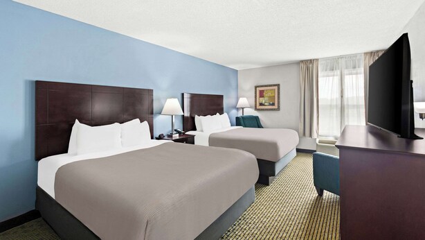 A hotel room with two beds, a flat-screen TV, a desk, and a window with curtains. - Quality Inn Dry Ridge (Dry Ridge)