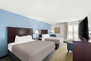 A hotel room with two beds, a flat-screen TV, a desk, and a window with curtains. - Quality Inn Dry Ridge (Dry Ridge)