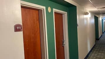 A hotel hallway with teal walls, wooden doors, and a patterned carpet.
