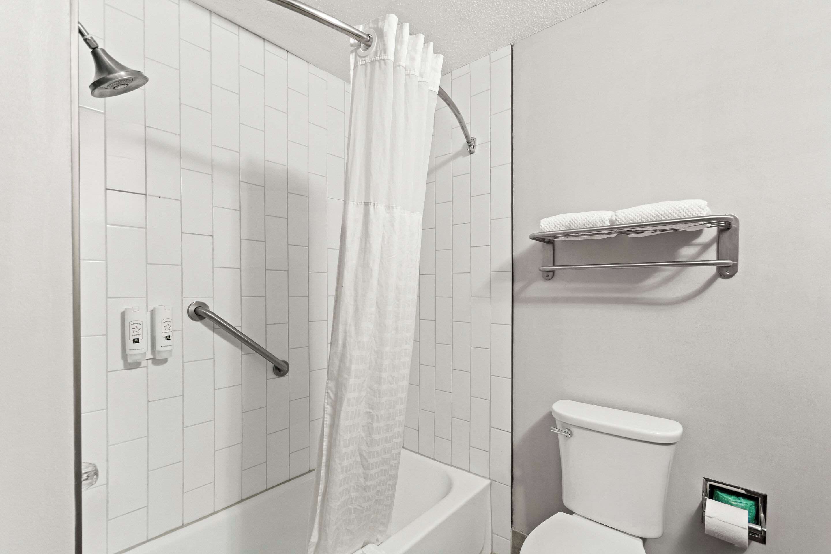 Un baño con ducha, inodoro y toallero.