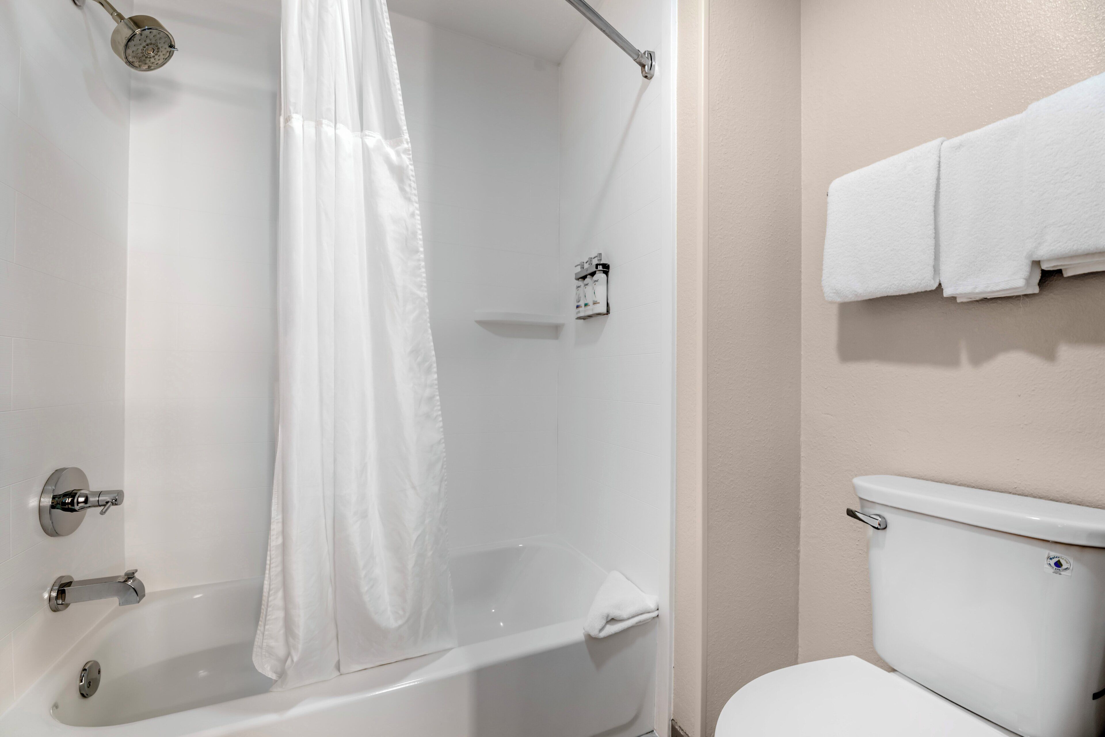 Un baño con bañera, cortina de ducha, inodoro y un perchero para toallas.