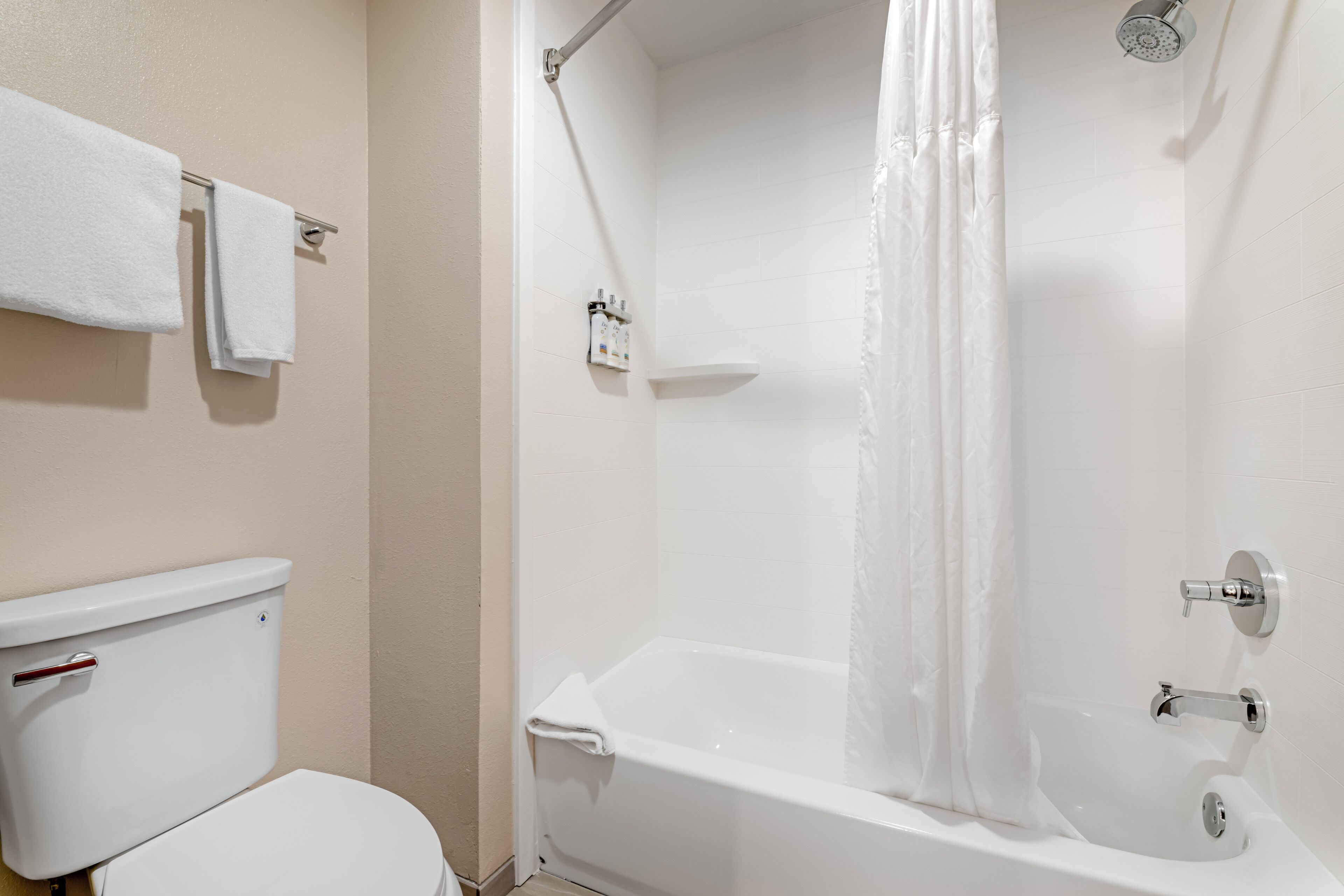 A bathroom with a toilet, a shower with a curtain, and a towel rack.