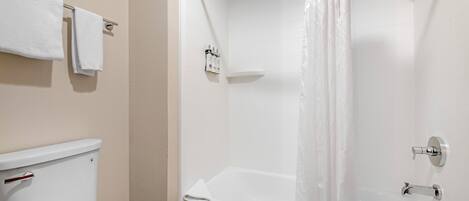 A bathroom with a toilet, a shower with a curtain, and a towel rack.