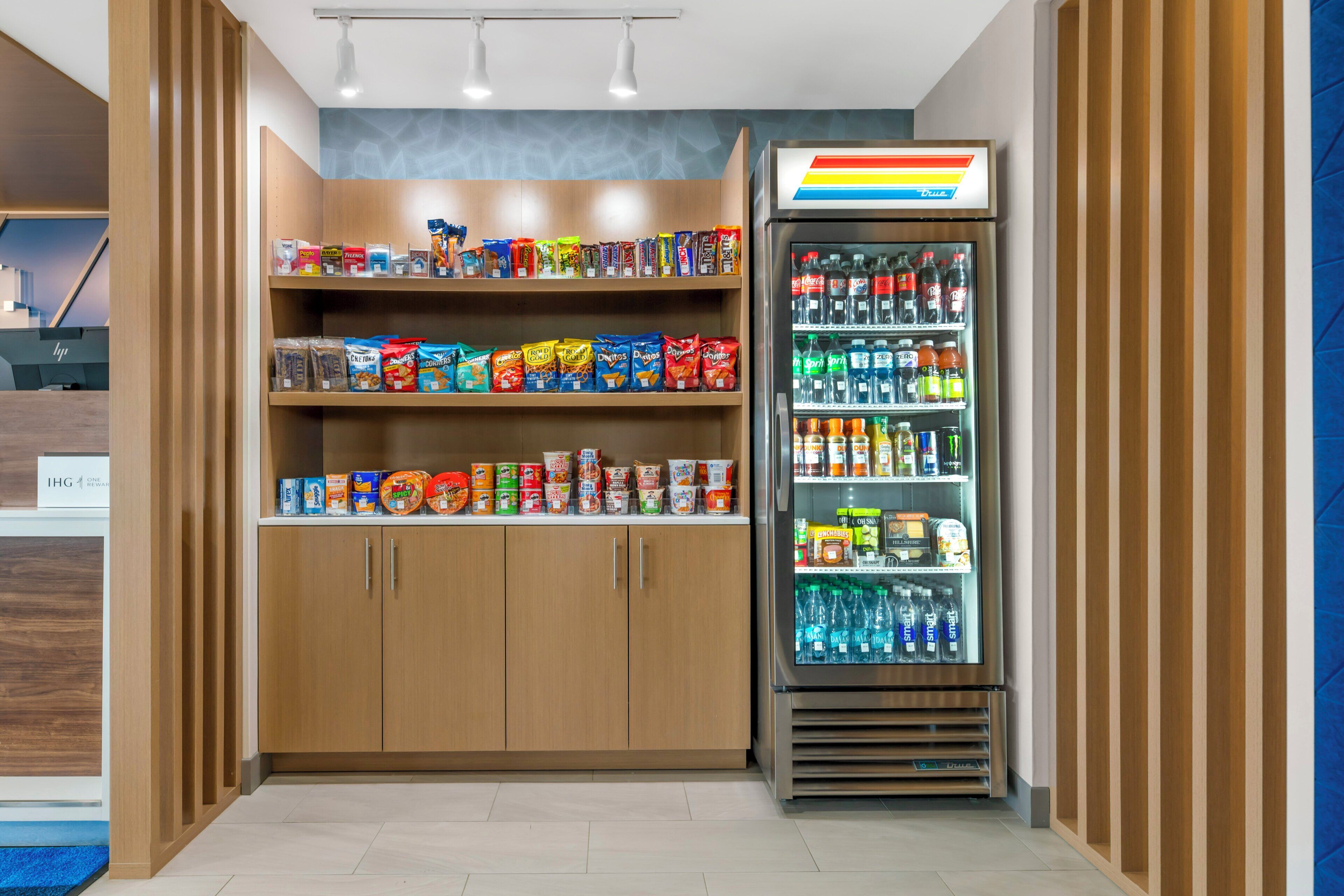 A snack and beverage vending area with multiple shelves stocked with various snacks and a refrigerated section with bottled drinks.