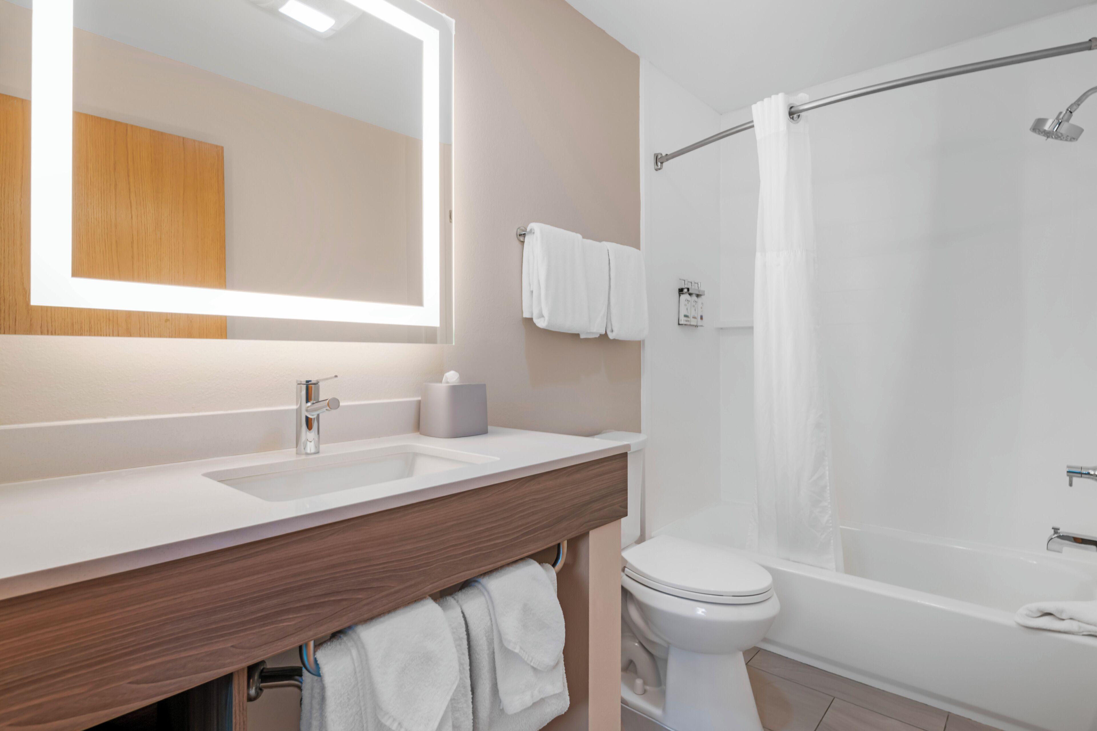A modern bathroom with a large mirror, two sinks, a toilet, and a shower.