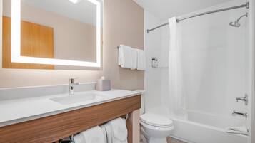 Un baño con un espejo grande, dos lavamanos, un inodoro y una bañera.