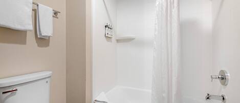 A bathroom with a toilet, a shower with a curtain, and a towel rack.