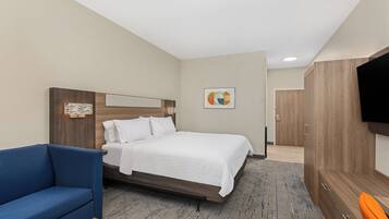 Une chambre d’hôtel avec un lit, un canapé bleu, une télévision et une armoire en bois.