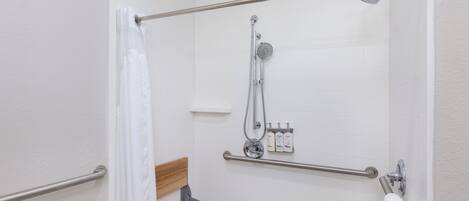 A shower area with a grab bar, a bench, and a towel rack.