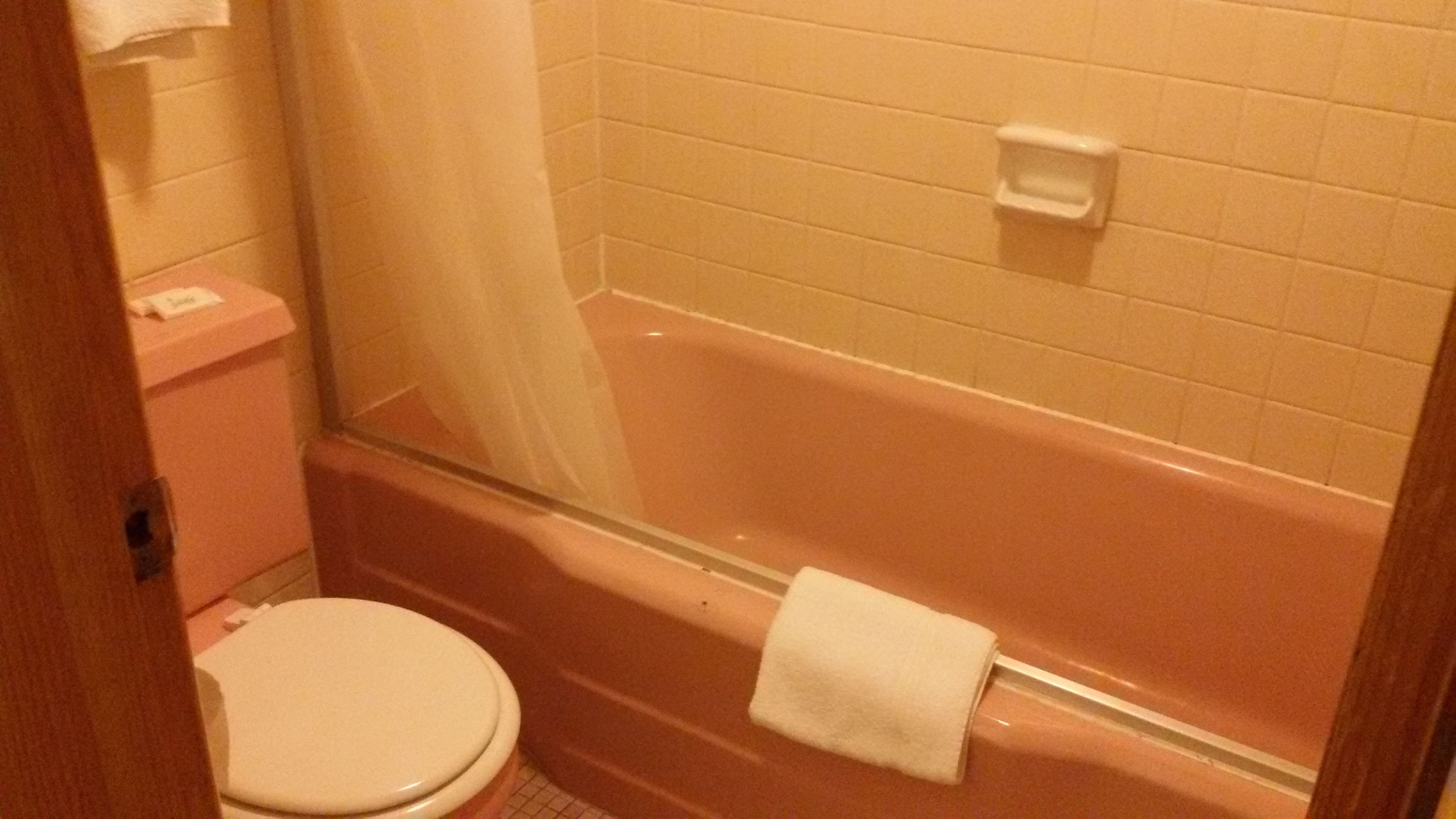 Un baño con inodoro blanco, bañera y cortina de ducha.