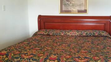 A bed with a floral-patterned bedspread and a wooden headboard.