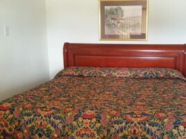 A bed with a floral-patterned bedspread and a wooden headboard.