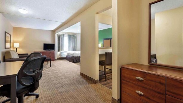 Une chambre d’hôtel équipée d’un bureau, d’une chaise, d’une télévision, d’un lit et d’une commode.